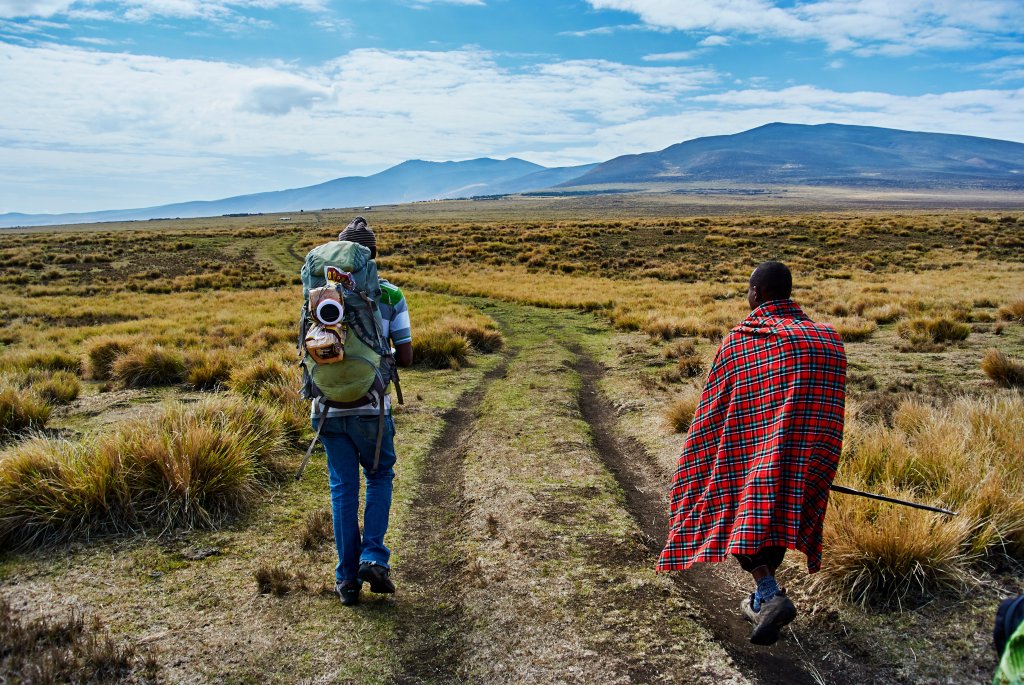 Zwei Wanderer marschieren durch die Ngorongoro Conservation Area in Tansania. 
