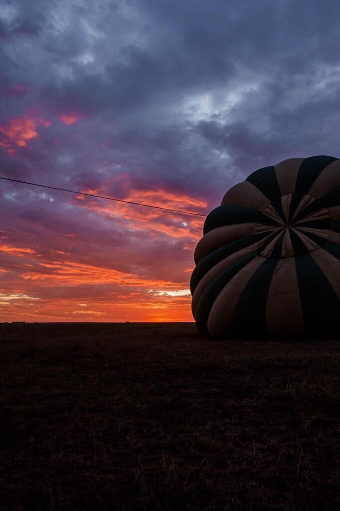 Bei Sonnenaufgang liegt einer Heißluftballon noch am Boden. In der Serengeti, Tansania, starten täglich mehrere Heißluftballone, um die Savanne von oben zu sehen. Ballon-Safaris beginnen schon sehr früh, um 6 Uhr morgens.