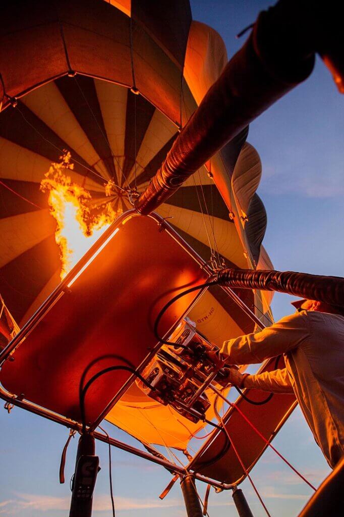 Bei Sonnenaufgang über der Serengeti befeuert der Pilot seinen Heißluftballon.
