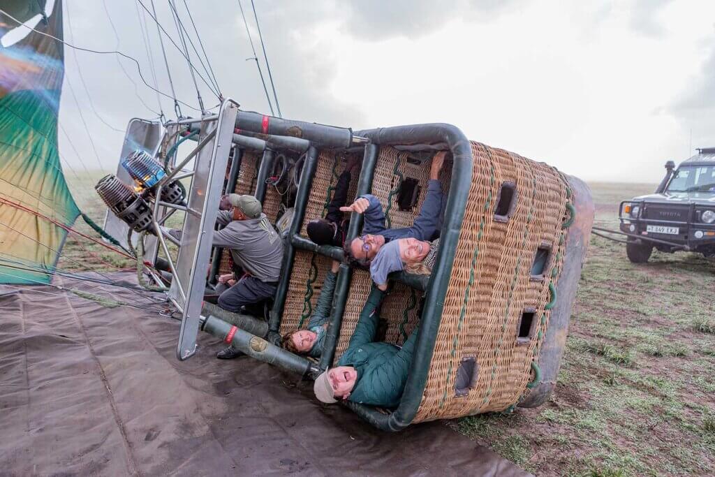 Ein Pilot ist in der Serengeti, Tansania, gerade dabei, einen Heißluftballon mit Passagieren im Korb aus liegender Position aufzurichten